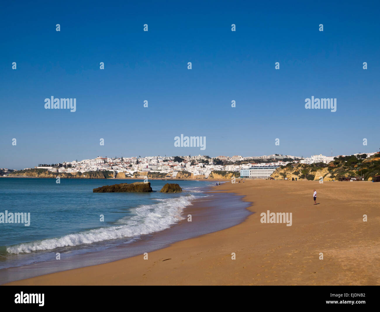 Persona che cammina da sola su una spiaggia deserta di inverno in Albufeira, Algarve, PORTOGALLO Foto Stock