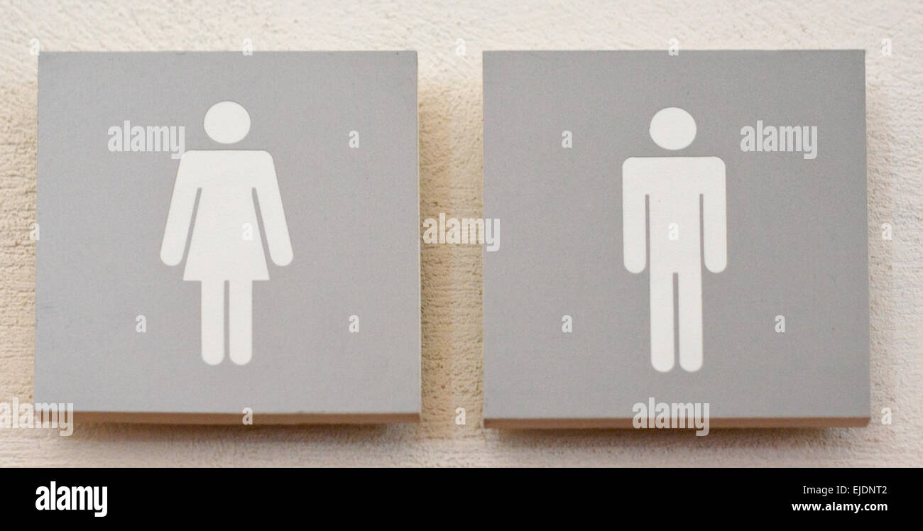 Donne e uomini segno servizi igienici, grigio su bianco sulla parete pietroso Foto Stock