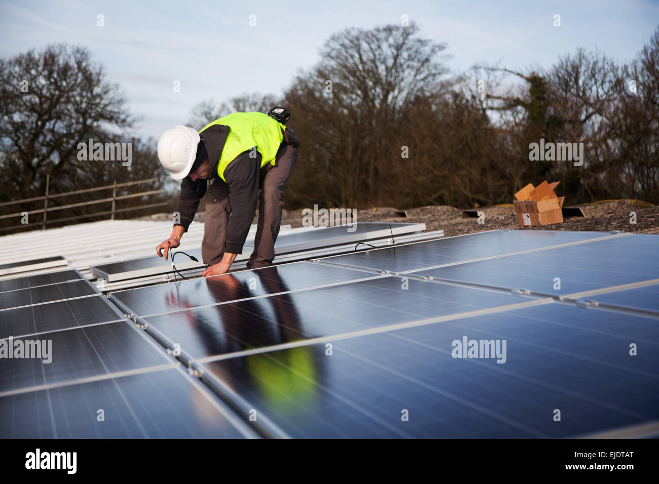 Jake Beautyman installa pannelli solari sul tetto del granaio su Grange farm, vicino Balcombe. L'installazione è parte di un'iniziativa di Foto Stock