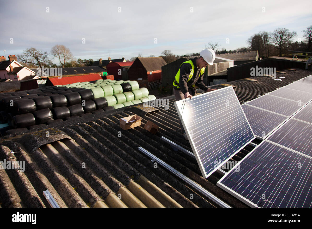 Jake Beautyman installa pannelli solari sul tetto del granaio su Grange farm, vicino Balcombe. L'installazione è parte di un'iniziativa di Foto Stock