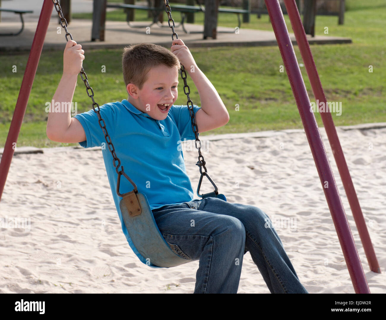 Bambino di otto anni swinging presso il park parco giochi Foto Stock