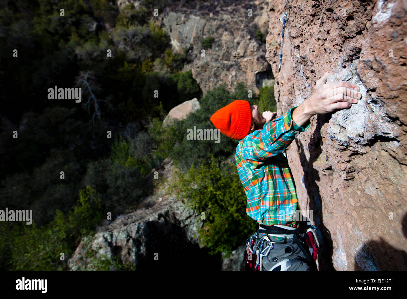 Un scalatore maschio in un arancione beanie e multicolori shirt salite gioiello di famiglia (5.10d) sul Monte meravigliosa in Malibu Canyon membro Foto Stock