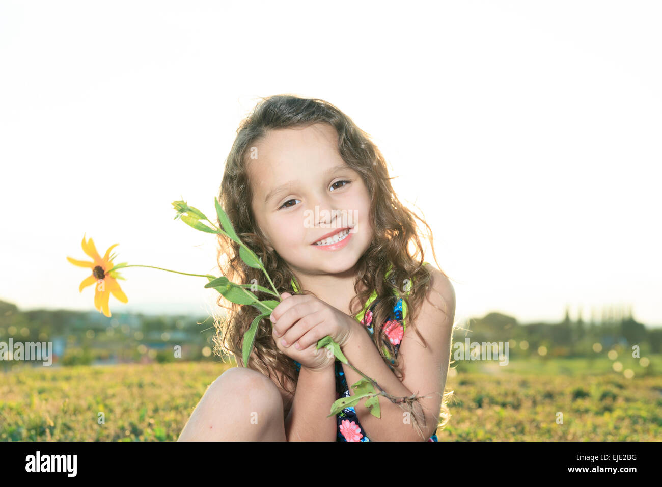 Bambina in sunset con fiore Foto Stock