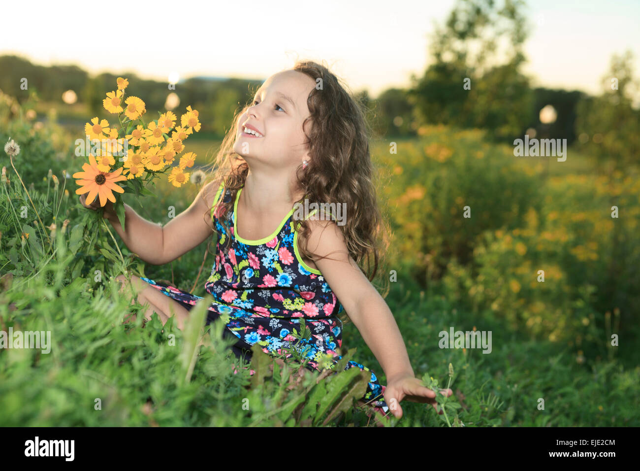 Bambina in sunset con fiore Foto Stock