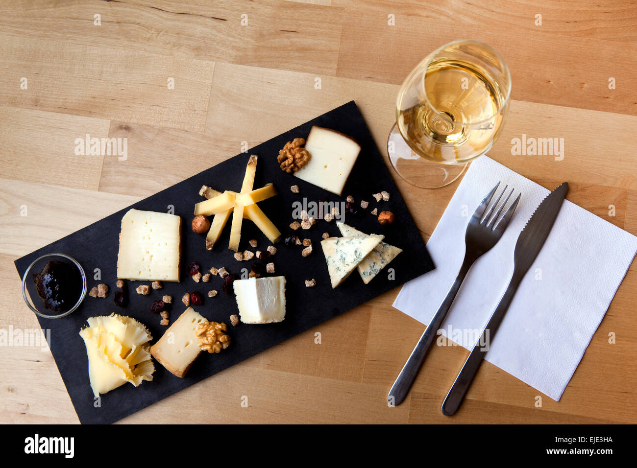 Piastra di vari formaggi e bicchiere di vino bianco su un tavolo Foto Stock
