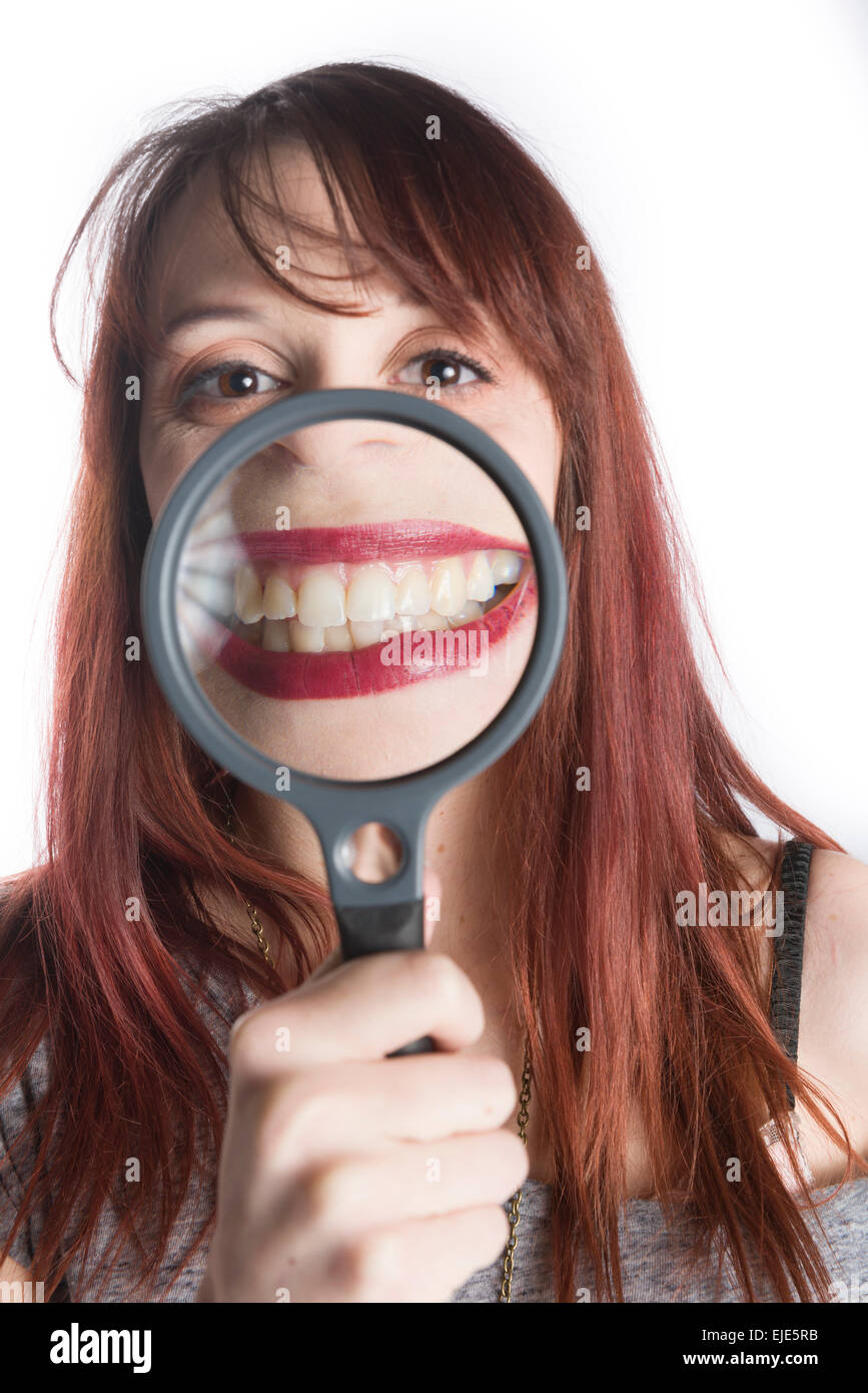 Giovane donna sorriso di Ingrandimento con lente di ingrandimento Foto Stock
