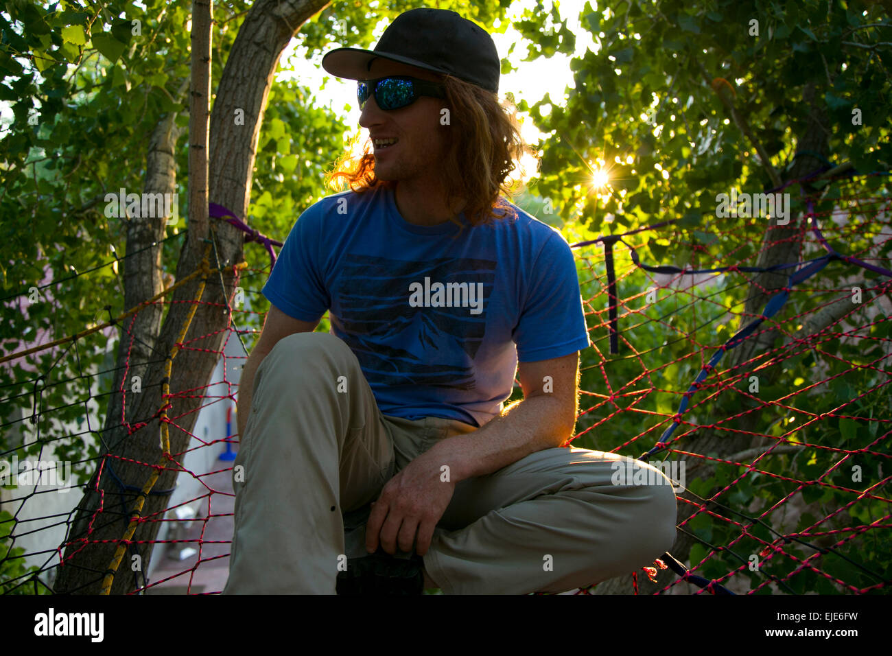 Un giovane uomo appeso fuori con gli amici in un fatta in casa tree net in Moab, UT Foto Stock
