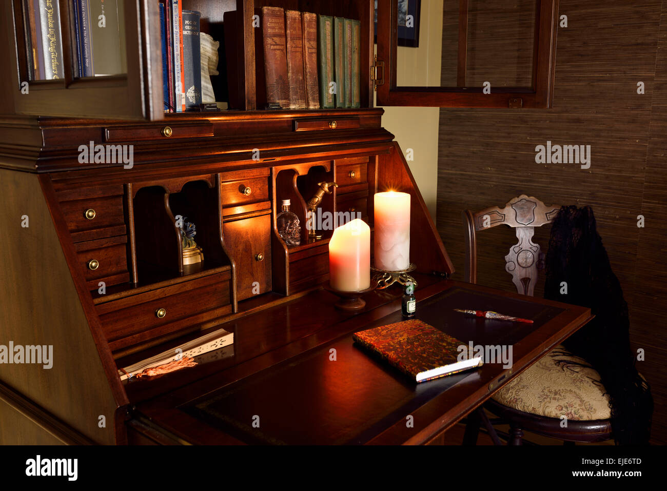 Classici in legno segretario scrivania in camera oscura con candele e sedia Foto Stock