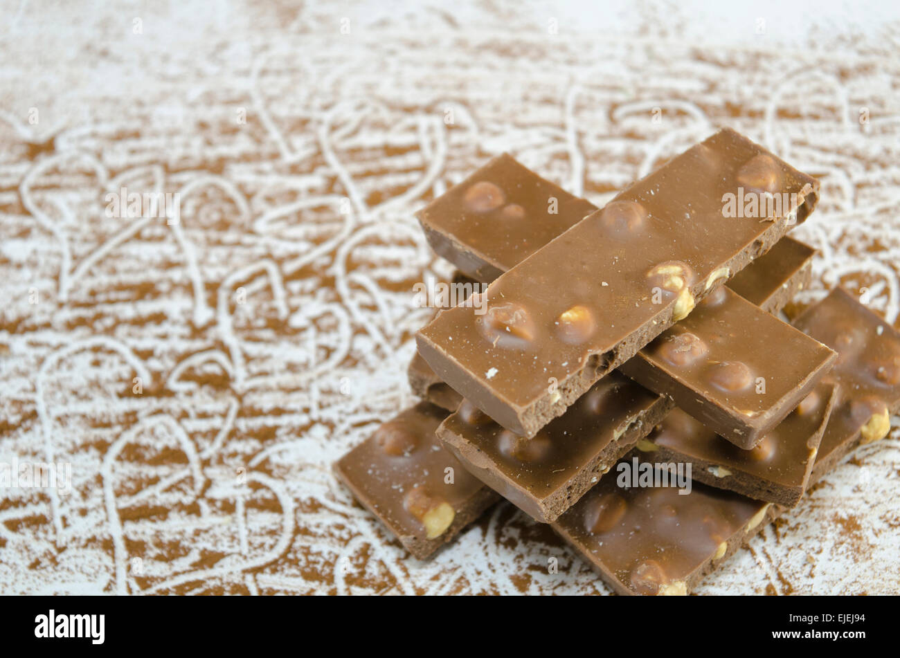 Tutto il cioccolato i dadi su un tavolo spruzzata con cacao decorate con disegnato a mano le forme di cuore Foto Stock