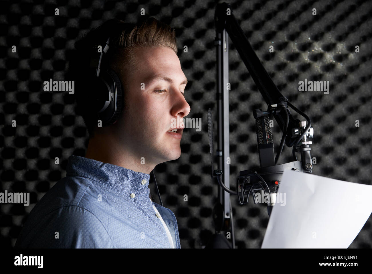 Uomo in studio di registrazione parlando nel microfono Foto Stock