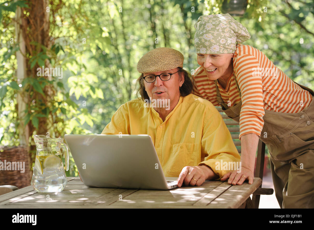 Coppia senior all aperto con un laptop, stanno guardando il computer. Eventualmente avente un wireless video chiamata con i nipoti. Foto Stock
