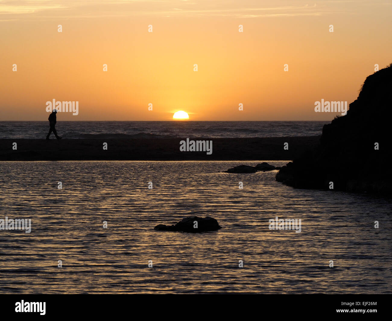 Uomo piccolo a Frame Walking Beach al tramonto sull'Oceano Pacifico Foto Stock