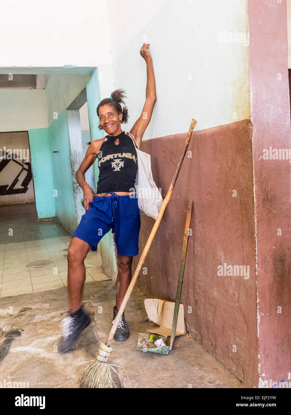 Una femmina di afro-cubane donna delle pulizie pose e sorrisi come ella si prende una pausa dal suo lavoro di pulizia presso il mercato pubblico. Foto Stock