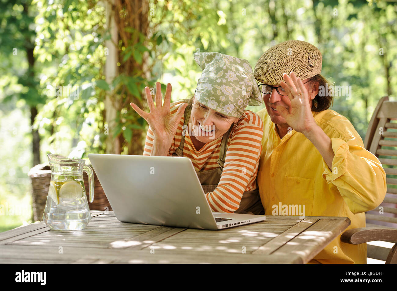 Coppia senior all aperto con un laptop, stanno guardando il computer. Eventualmente avente un wireless video chiamata con i nipoti. Foto Stock