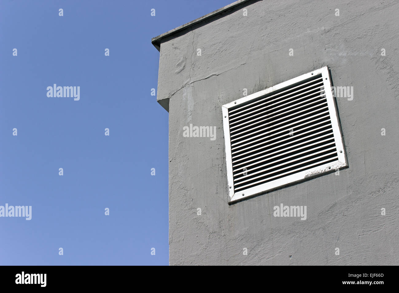 Finestra di ventilazione su grigio muro di cemento con cielo blu Foto Stock