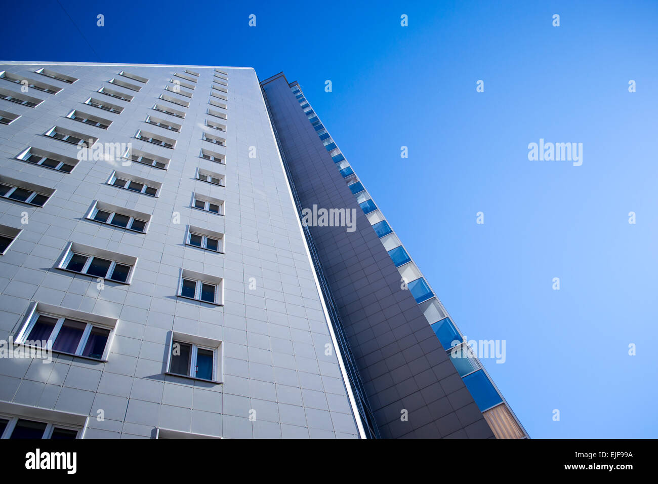 Un triangolo a forma di blocco di appartamenti si estende nel cielo blu con copyspace Foto Stock