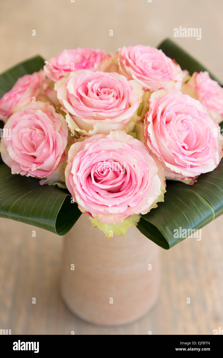 Pizzi-orlato pastello attraenti le rose rosa in un elegante stile bouquet composizioni floreali con foglie di banano nel vaso in terracotta Foto Stock