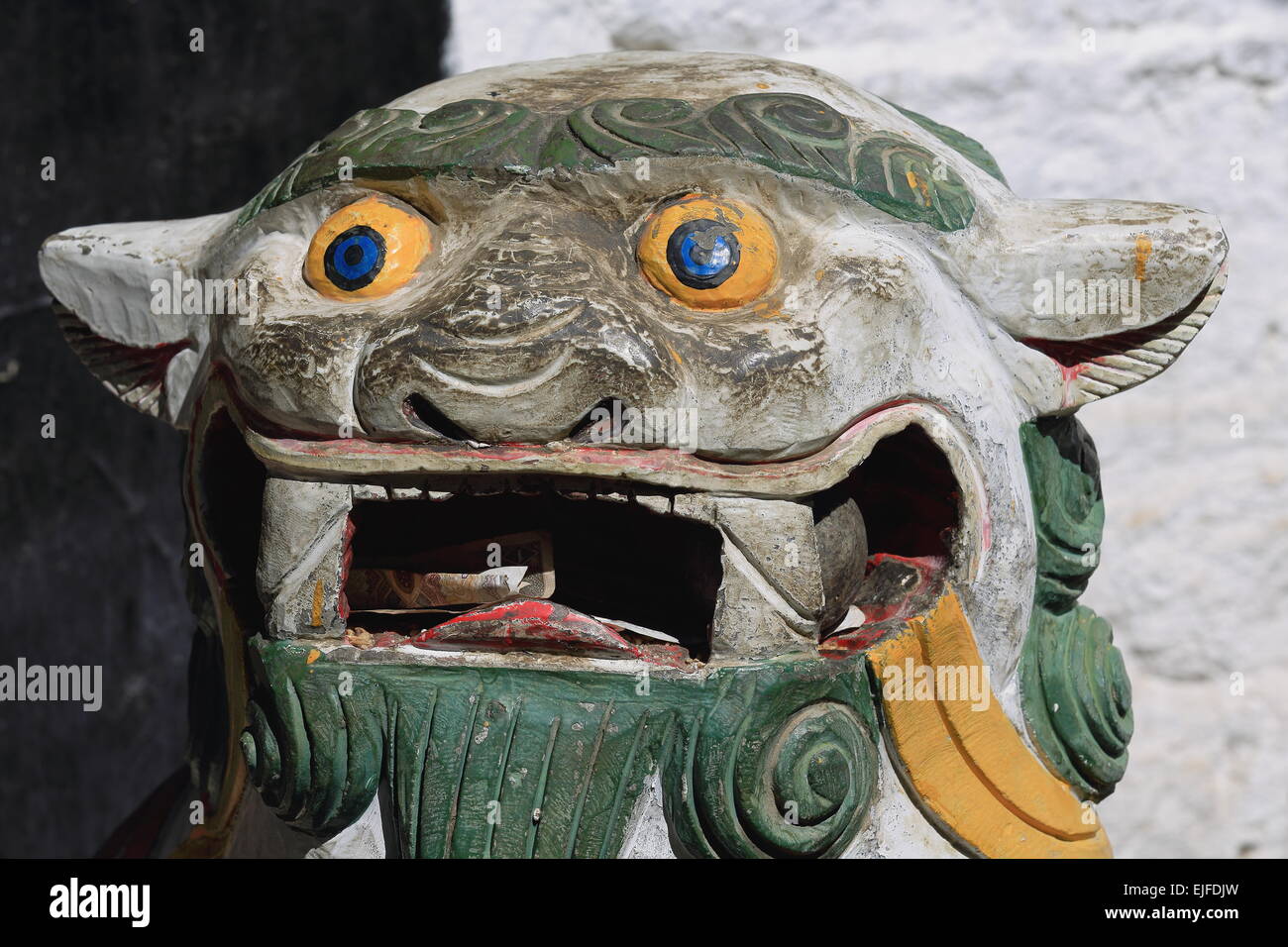 Neve leone carving con offerte di devoti-denaro banconote in bocca al di fuori del Takten Mingyur Phodrang-Eternally Unchange Foto Stock