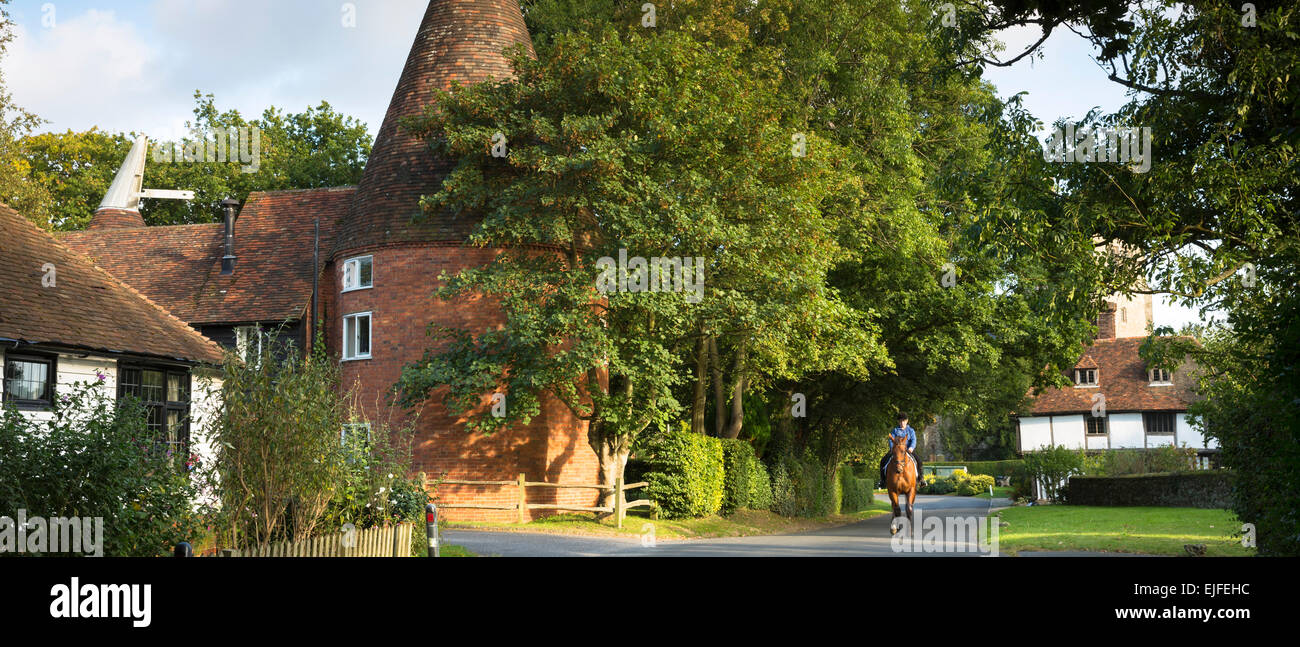 Cavallo e cavaliere nel pittoresco villaggio affascinante di Smarden con tradizionale Kentish oast house in alta Weald nel Kent, England, Regno Unito Foto Stock