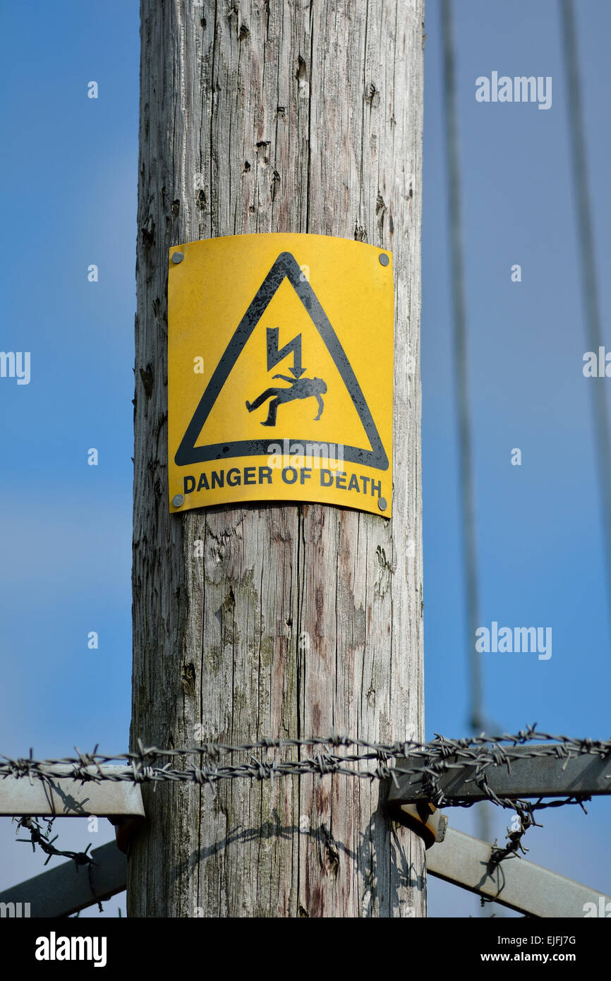 Pericolo di morte in segno di avvertimento sul palo di legno che trasportano la fornitura di elettricità Foto Stock