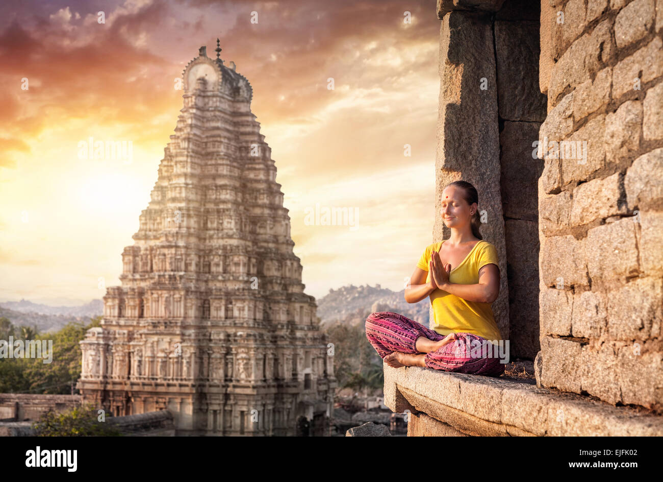 Donna con Namaste mudra seduta vicino Tempio Virupaksha in Hampi, Karnataka, India Foto Stock