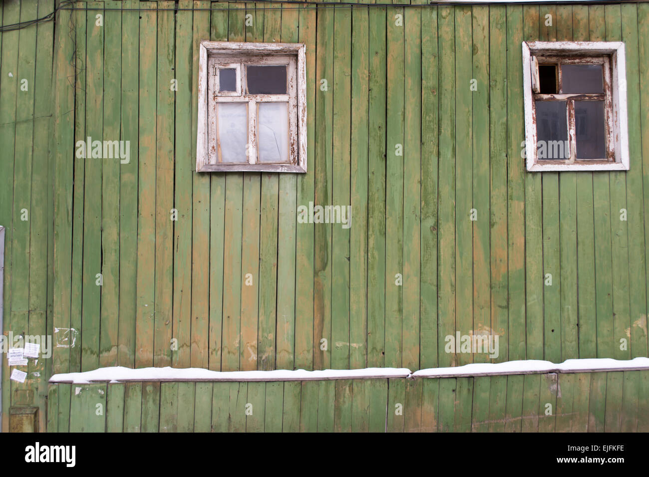 Un dipinto di verde casa in legno parete con invecchiamento di due telai di finestra Foto Stock