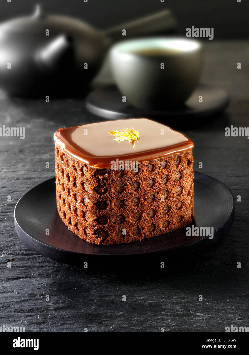 Una specialità di pasticceria fatta a mano ricca di dolci al cioccolato con tè in un ambiente nero Foto Stock