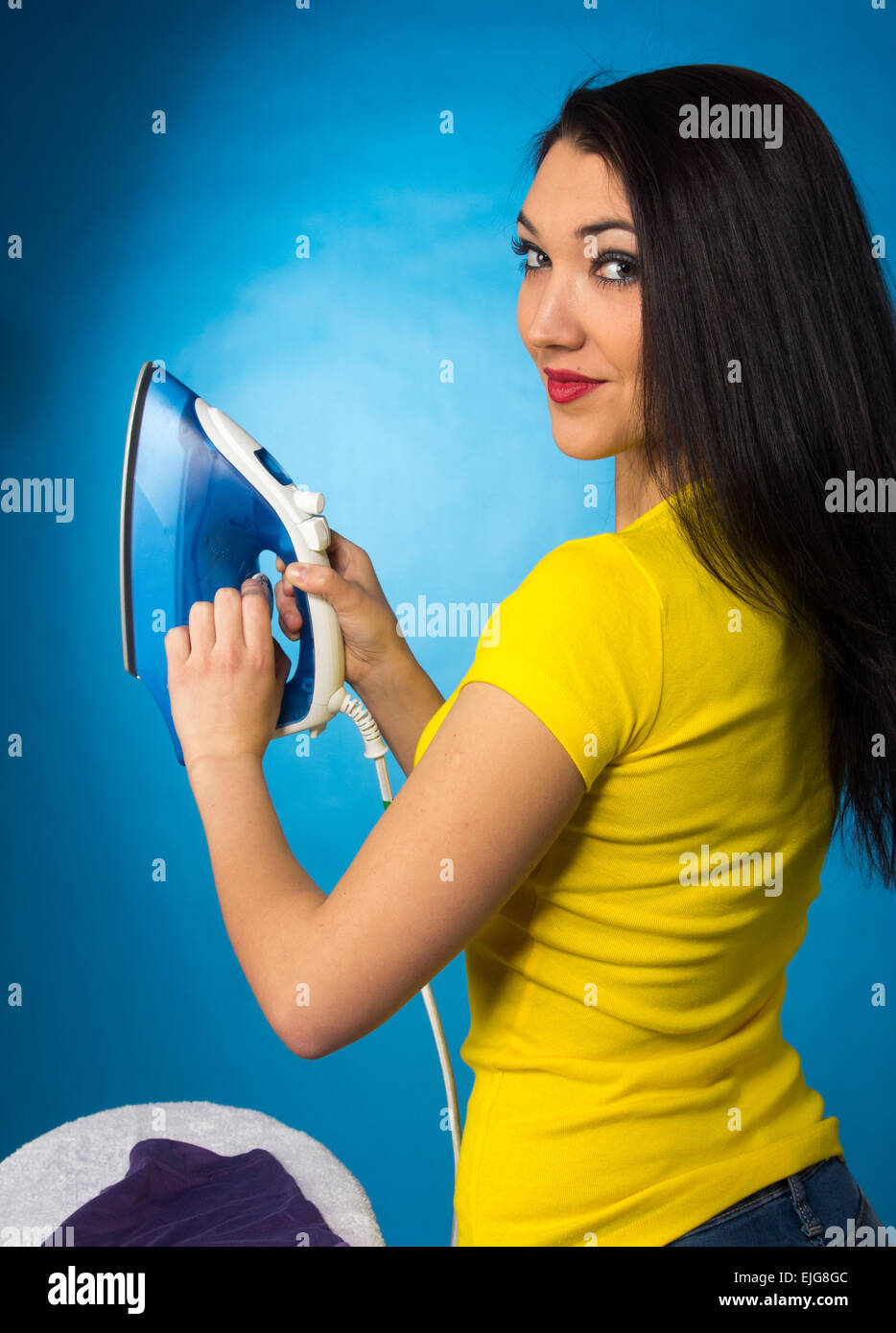 Houseworks, donna con il mucchio di vestiti per la stiratura, su sfondo blu Foto Stock
