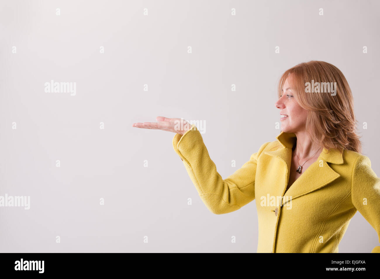 Donna bionda in giallo ricoprire risalendo la sua mano per tenere il tuo spazio di copia Foto Stock