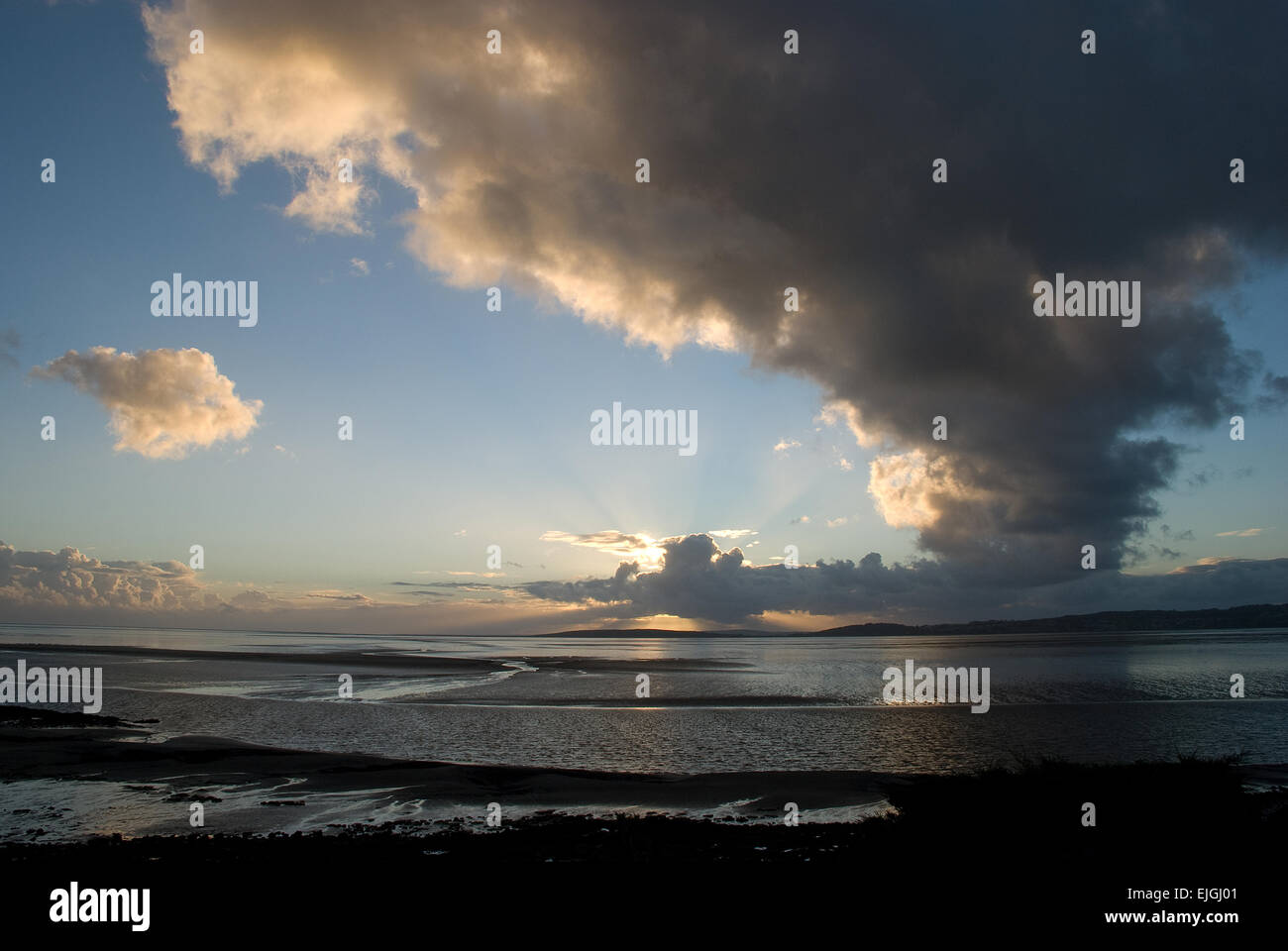 Il tramonto è mozzafiato, con le affascinanti nuvole curvate e il cielo blu che attraversa la baia di Morecambe nel Lancashire Foto Stock