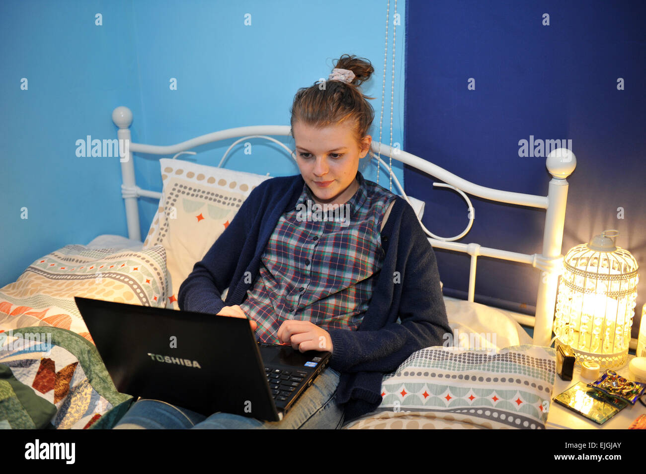 Una ragazza adolescente utilizza il suo computer portatile nella sua camera da letto. Modello rilasciato Foto Stock