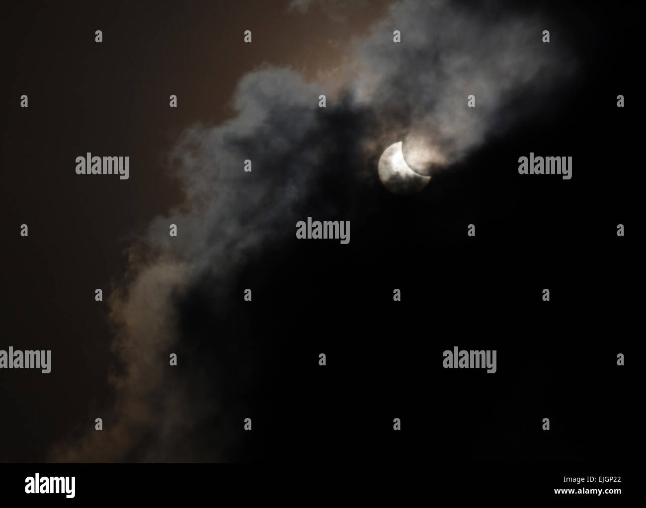 Vista parziale eclissi solare dietro le nuvole Foto Stock