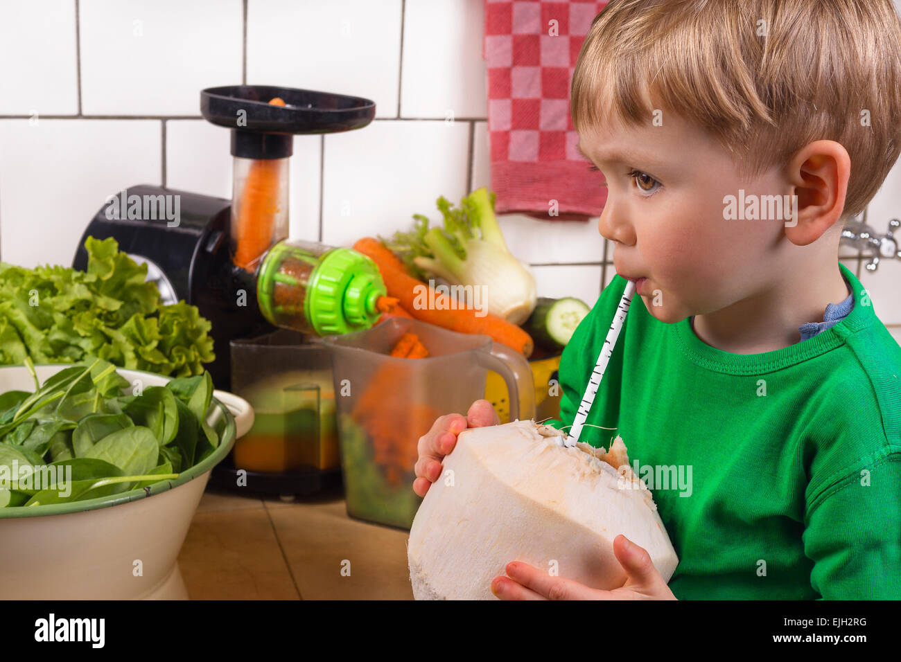 Carino toddler giovani bere acqua di cocco in cucina. Foto Stock