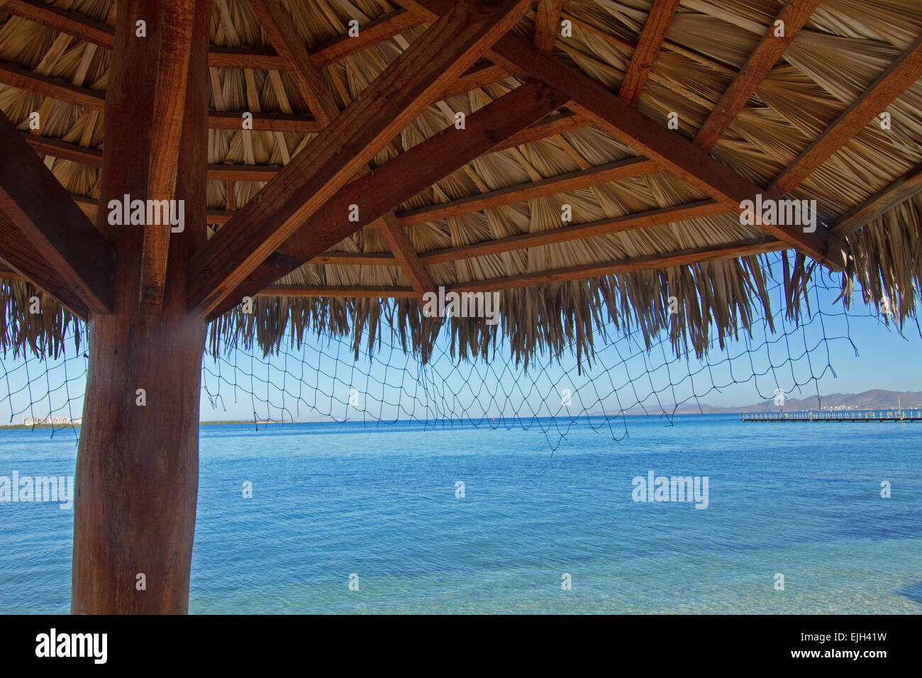 Un palm thatch ombrello proietta ombra Baja Beach. Foto Stock