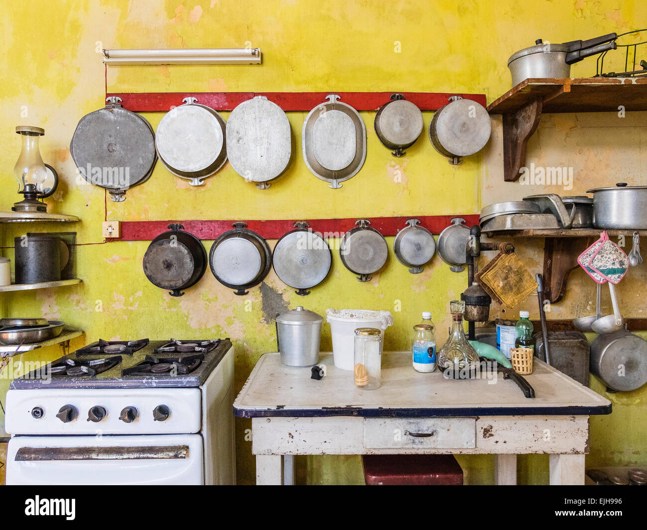Una vista della stufa e tavolo di lavoro accanto ad essa e molte pentole e padelle appeso alla parete al di sopra di esse in una cucina di una casa cubana. Foto Stock