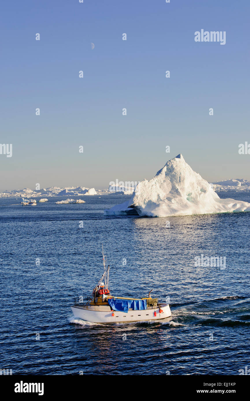 Una barca da pesca in direzione di porto di Illulisat, Groenlandia. Iceberg in background Foto Stock