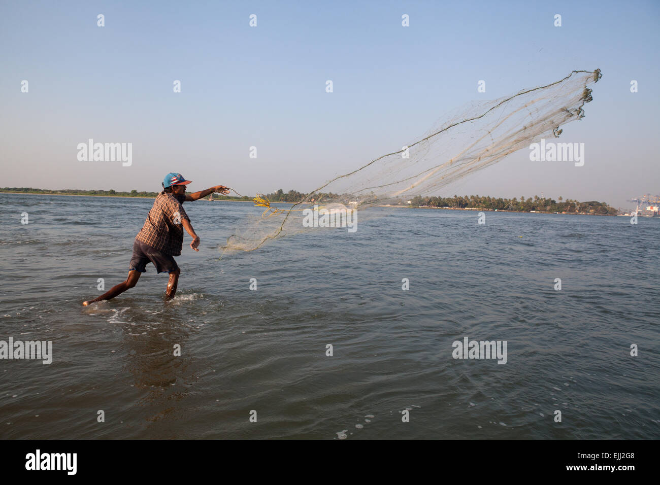 Pescatore getta la sua rete in mare Foto Stock