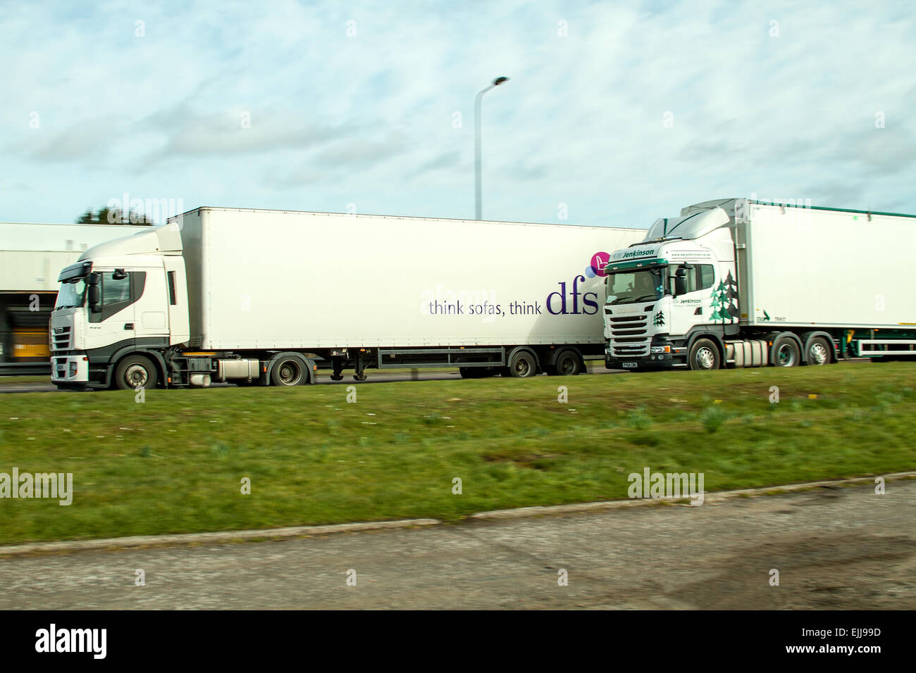 Una DFS autoarticolato sorpassi un A.W Jenkinson Prodotti forestali camion lungo il Kingsway a doppia carreggiata a Dundee, Regno Unito Foto Stock