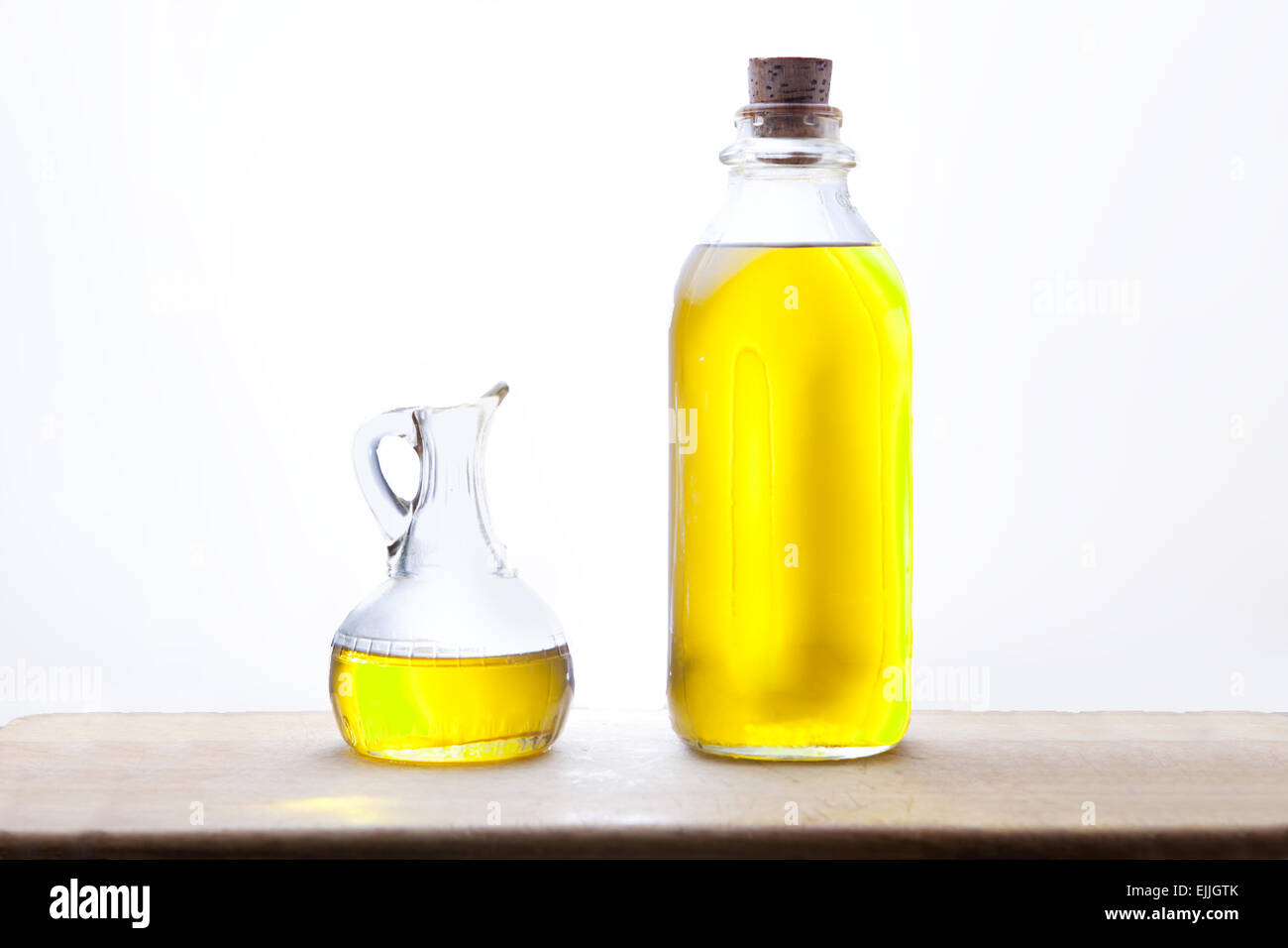 Olio di oliva Bottiglia ampolla e isolate su sfondo bianco, disposto su una superficie di legno Foto Stock