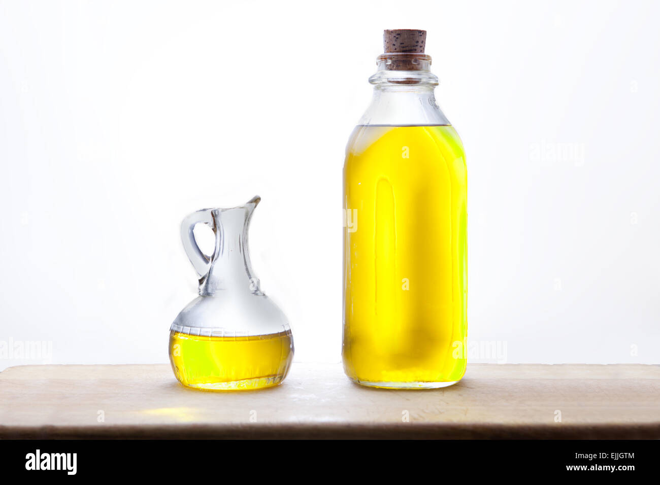 Olio di oliva Bottiglia ampolla e isolate su sfondo bianco, disposto su una superficie di legno Foto Stock
