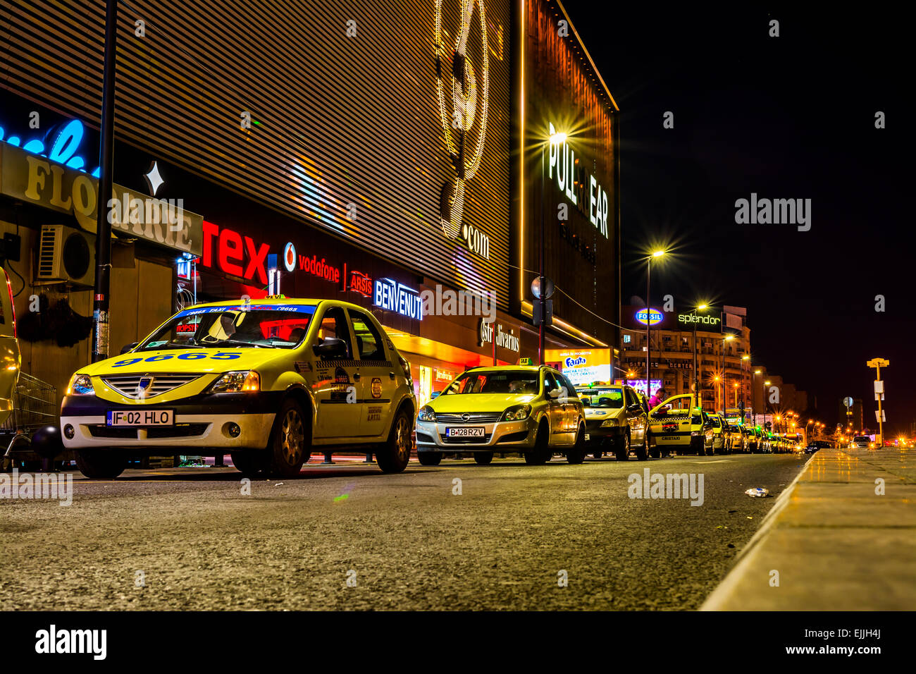 Una linea di taxi davanti a vetture di shopping centre, a Bucarest a notte. Foto Stock