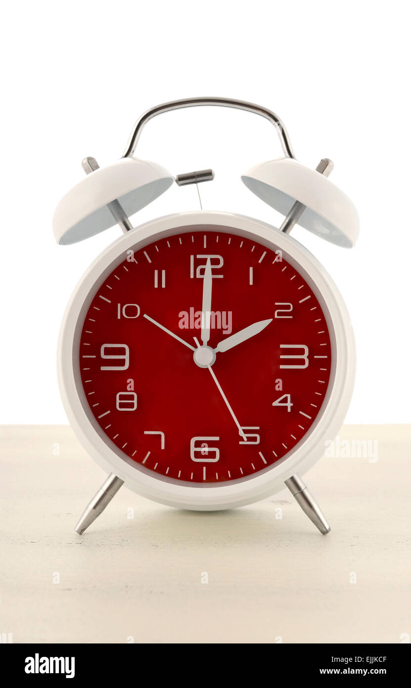 Ora legale con uno stile rétro orologio sveglia con faccia rossa bianco su uno sfondo di legno. Foto Stock