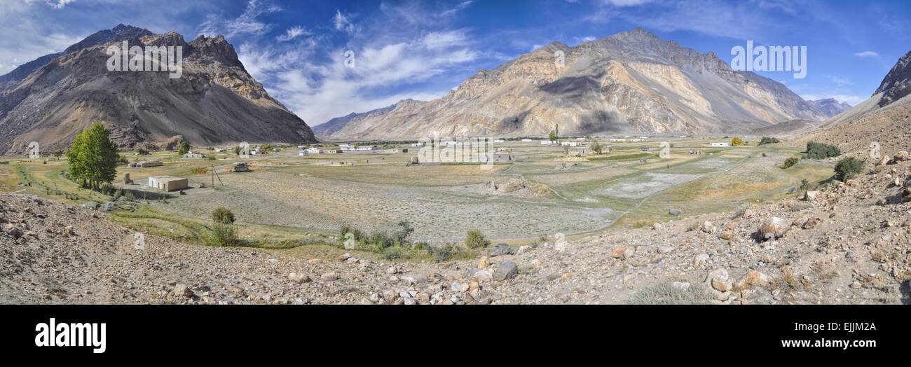 Suggestivo panorama del piccolo villaggio remoto con campi di grano in Tagikistan sul giorno di sole Foto Stock
