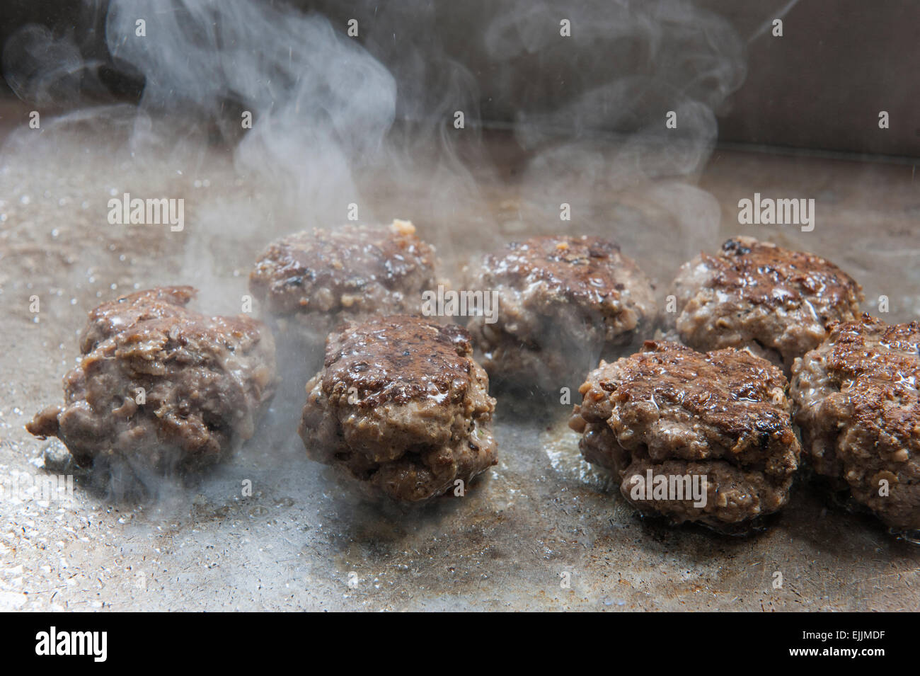Primo piano di polpette di carne bovina per la cottura sulla griglia a piastra calda a un hotel ristorante a buffet Foto Stock