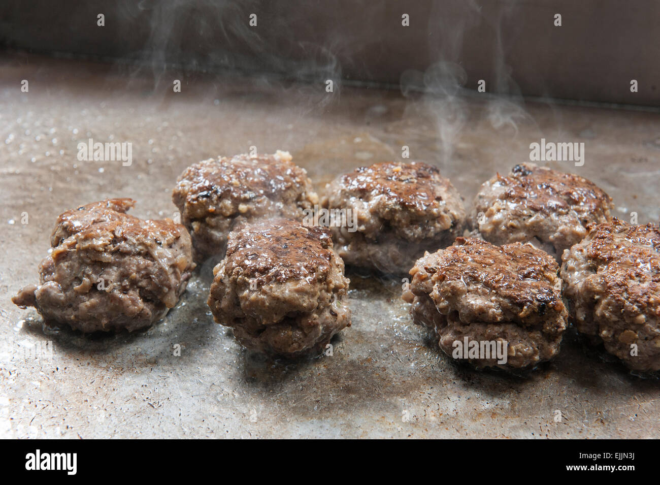 Primo piano di polpette di carne bovina per la cottura sulla griglia a piastra calda a un hotel ristorante a buffet Foto Stock