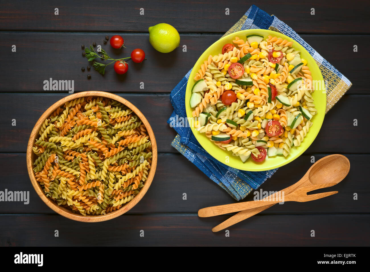 Colpo di overhead di materie fusilli nella ciotola di legno e un piatto di pasta vegetariana insalata Foto Stock