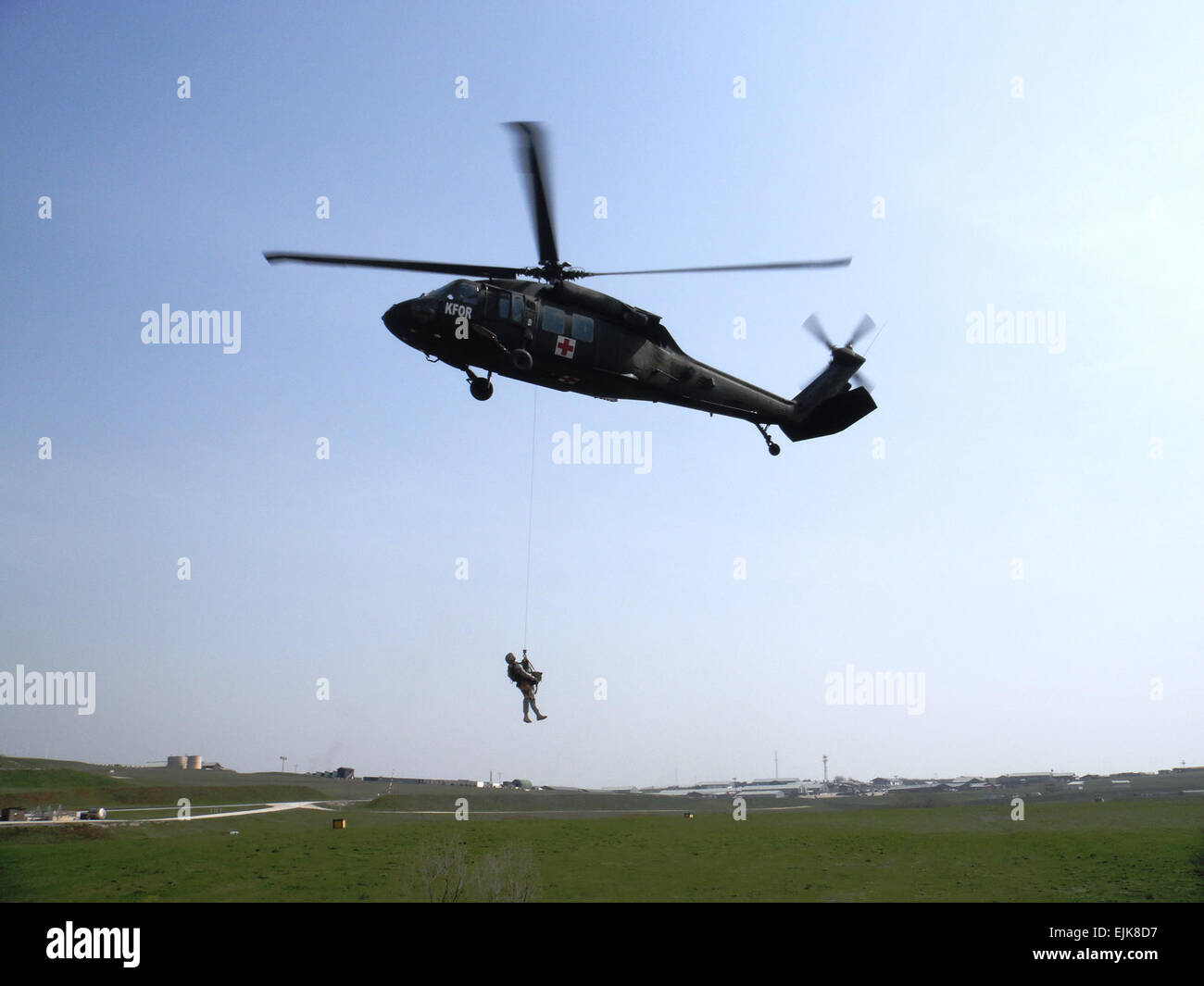 Il personale Sgt. Josh Rose, un cane militare handler e sottufficiale in carica del Camp Bondsteel fossa di scolo del cane, è issata skyward oltre 50 piedi, con suoi militari cane da lavoro, paraurti, ad un bilico UH-60 Black Hawk elicottero a Camp Bondsteel, Kosovo, 2 aprile. Il team del cane ha collaborato con aria medevac equipaggi dal Louisiana Guardia Nazionale il 2° Battaglione, 135Reggimento di aviazione di treno su procedure necessarie per evacuare un cane ferito da un campo di battaglia del pregiudizio. Il cap. Nathan Carlton, 61st multifunzionale battaglione medico Foto Stock