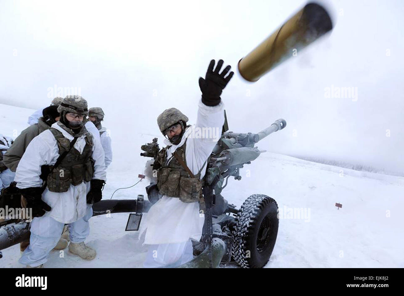 Stati Uniti Pfc dell'esercito. Cody Teel, sinistra, orologi come Spc. Mohammed Abbas getta una spesa 105mm obice shell durante il live-formazione antincendio su base comune Elmendorf-Richardson, Alaska, Dic 18, 2013. Teel e Abbas sono assegnati per il XXV divisione di fanteria il 2° Battaglione, 377 campo paracadute reggimento di artiglieria, quarta brigata di fanteria Team di combattimento, Alaska. Justin Connaher Foto Stock