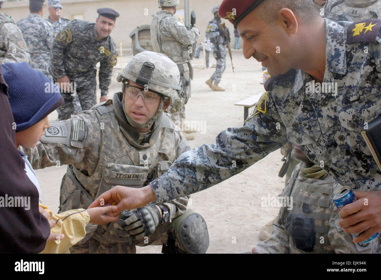 Lt. Col. Louis Zeisman, nativo di Fayetteville, N.C., comandante del secondo battaglione, 505th Parachute Reggimento di Fanteria, 3° Brigata Team di combattimento, ottantaduesima Airborne Division, Divisione Multinazionale a Baghdad e una nazionale iracheno funzionario di polizia dare un ragazzo iracheno qualche caramella durante una scuola di distribuzione alimentazione caso Feb. 19 Al Assal Kindergarten nella città di Oubaidy. L'Al Assal scuola materna è stata una delle due scuole a ricevere gli elementi di scuola dalle forze combinate. I paracadutisti sono state assistendo i loro partner iracheno in Oubaidy e tutta nuova Baghdad per diverse settimane per migliorare la vita Foto Stock