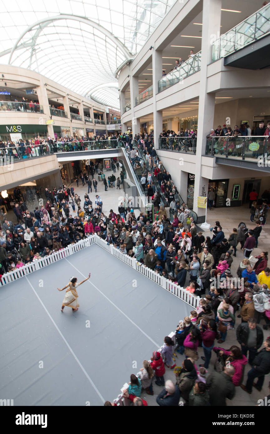 Gli amanti dello shopping e una strada performer dancing in Trinity shopping centre, Leeds Foto Stock